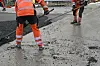 Fersk asfalt jevnes ut ved veikanten.