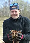 Arne Joar Hamland viser fram kongler som skal brukes som fyll på et av områdene ved diskgolfbanen under dugnadsarbeidet i Rørvik.