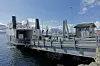 Bildet viser MF Helgøy, ved brygga i Hansnes, med Reinøya på andre siden av sundet. Bildet er tatt 6. mai 2019, en solrik dag på våren i Nord-Norge.