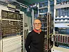 Bak ham ser vi en imponerende samling av gammelt telekommunikasjonsutstyr, en del av hans dedikerte arbeid med å bevare og dokumentere telehistorien.