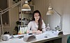 Angelika Zydron bak arbeidsbenken, omringet av verktøy og materialer som brukes til å skape vakre negledesign.