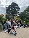 Ungdomsgruppe poserer samlet i en park under en overskyet himmel.