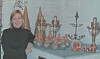 Kvinne ved et bord med antikke lysestaker, figurer og dekorative gjenstander.