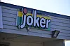 Joker-logo på en butikkfasade med grå trekledning.