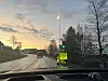 Våt vei med bil, lysregulering og et gult veiarbeidsskilt i et boligområde.