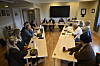 Møte med flere personer rundt langbord i et lyst konferanserom.