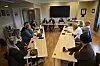 Møte med flere personer rundt langbord i et lyst konferanserom.